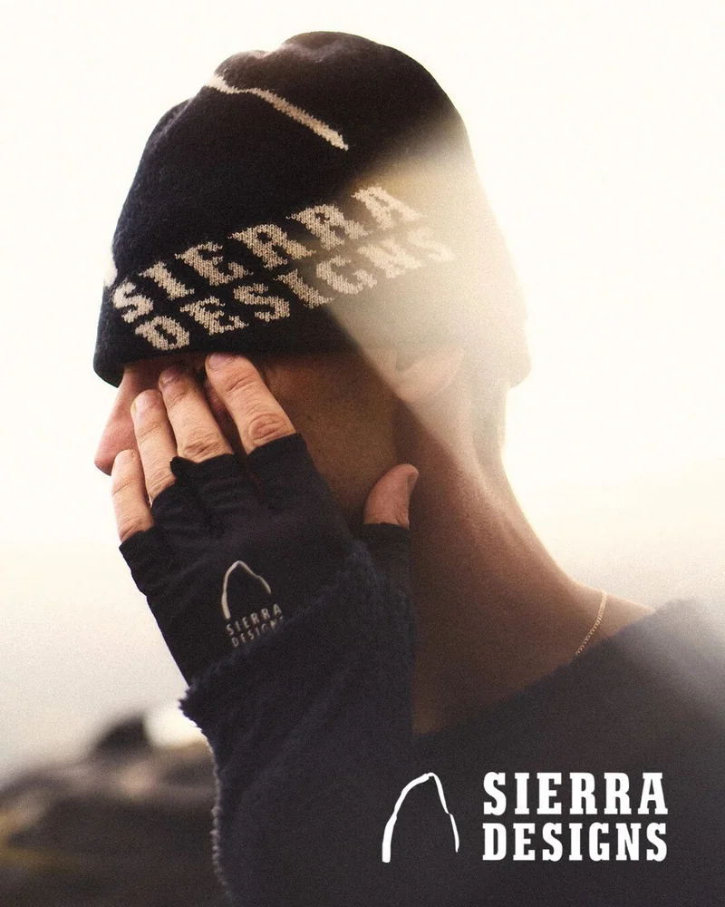 戴着 Sierra Designs 手套的人在戶外抬手遮擋陽光