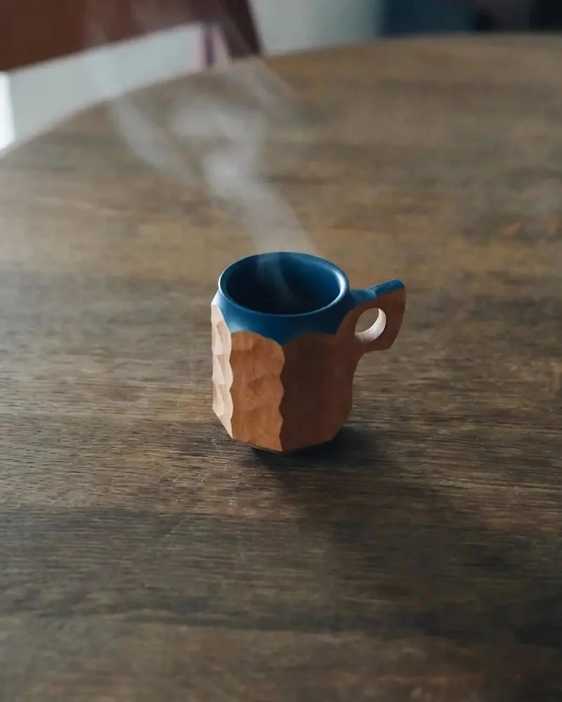 A wooden JINCUP with a blue interior held in a hand.