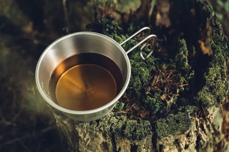 裝有熱飲的金屬雪拉碗放在苔蘚與岩石上