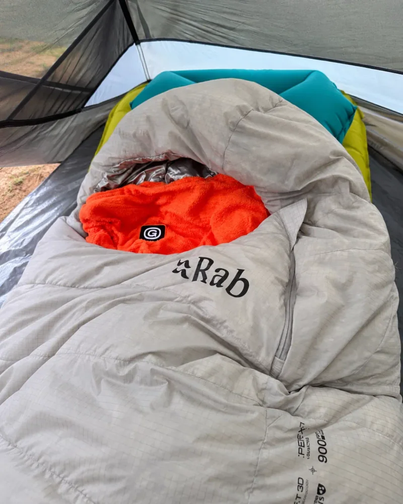 帐篷内铺开的灰白色 RAB 睡袋与橙色衣物
