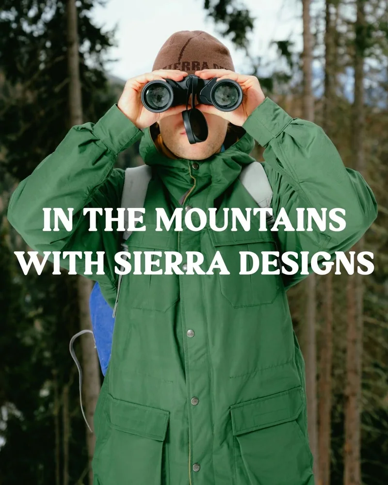 穿綠色 Sierra Designs 外套的人在山地環境舉起相機