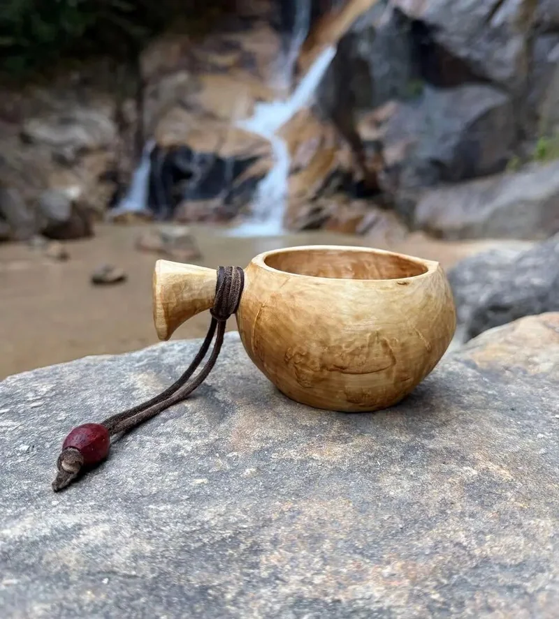 岩石旁放着繫有皮繩的傳統木杯