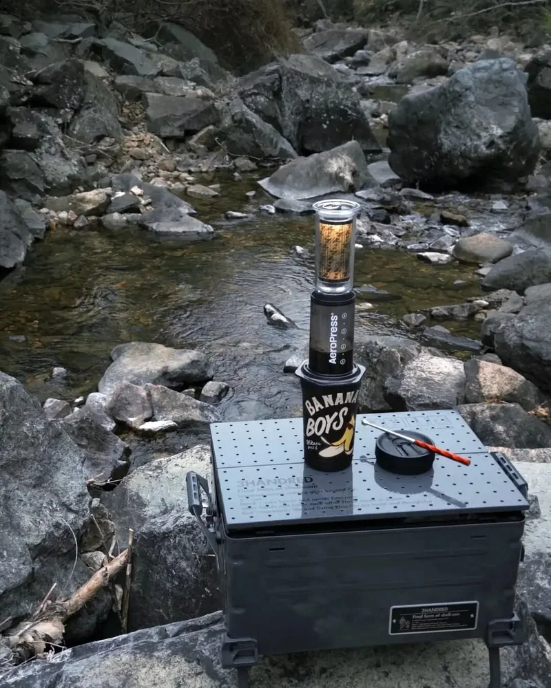 溪流邊桌面上的咖啡與發光杯