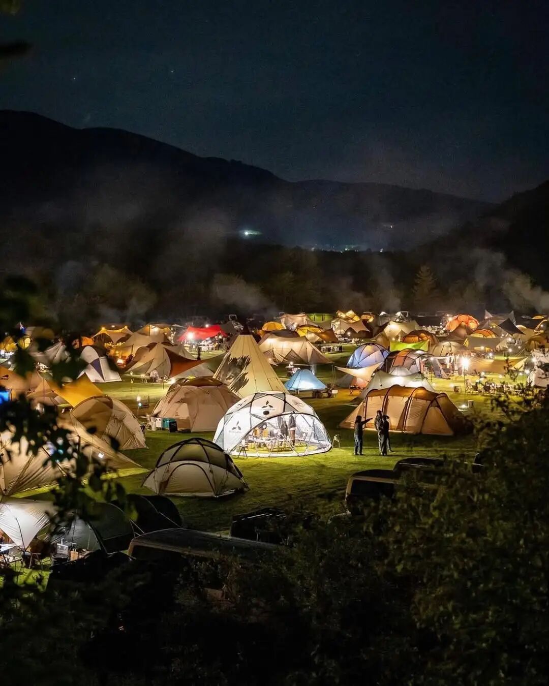 山林营地中密集亮起的帐篷与灯光