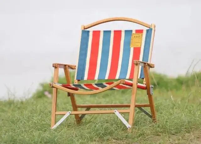 红白蓝 Retro Stripe 椅面的木制 Kermit Chair 摆在草地上
