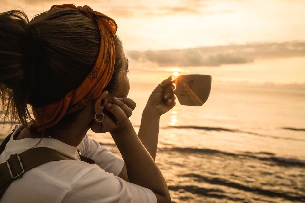 水边人物手持木杯的夕阳侧影