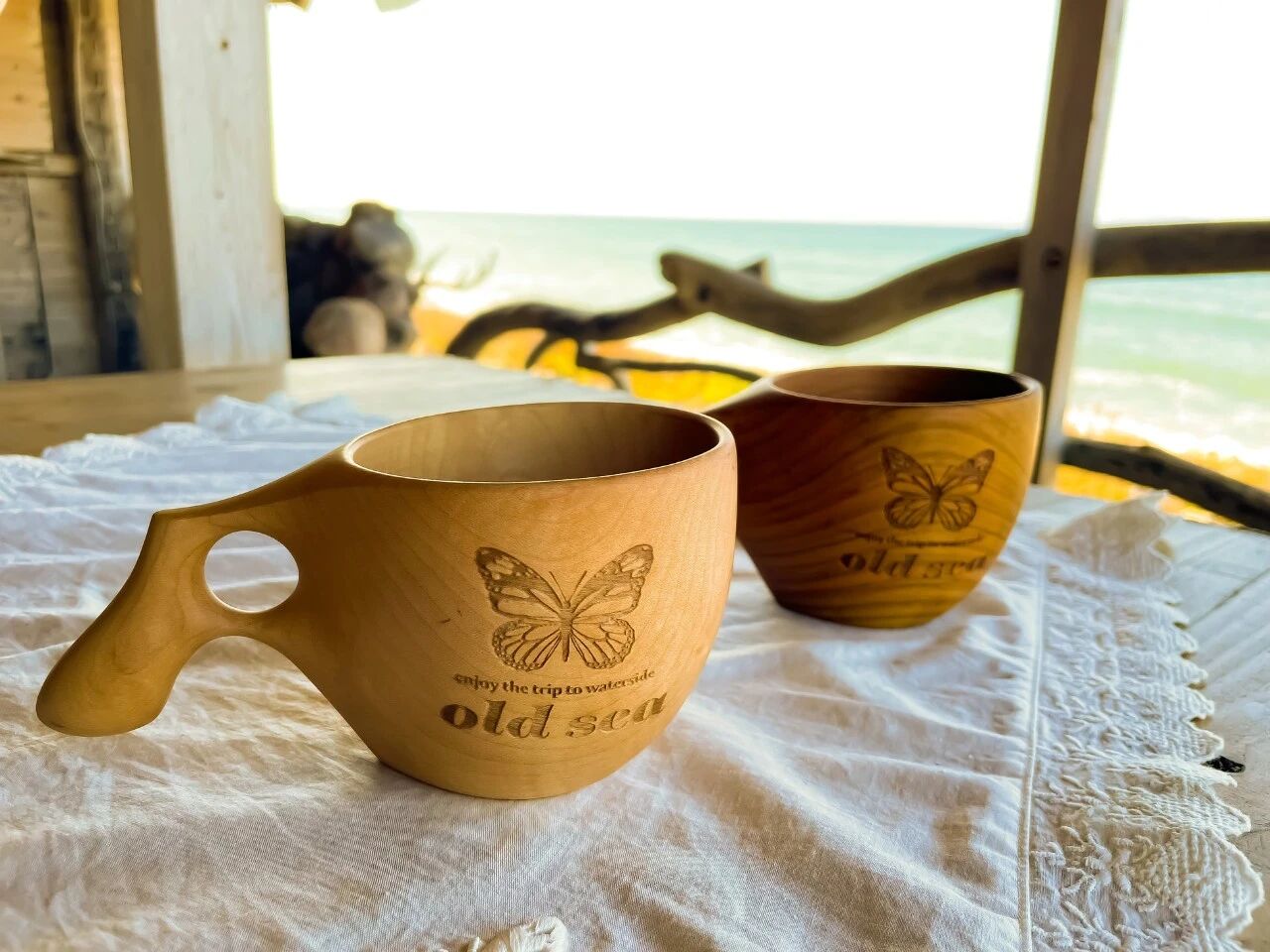 两只 OLD SEA 木杯放在夕阳水面前