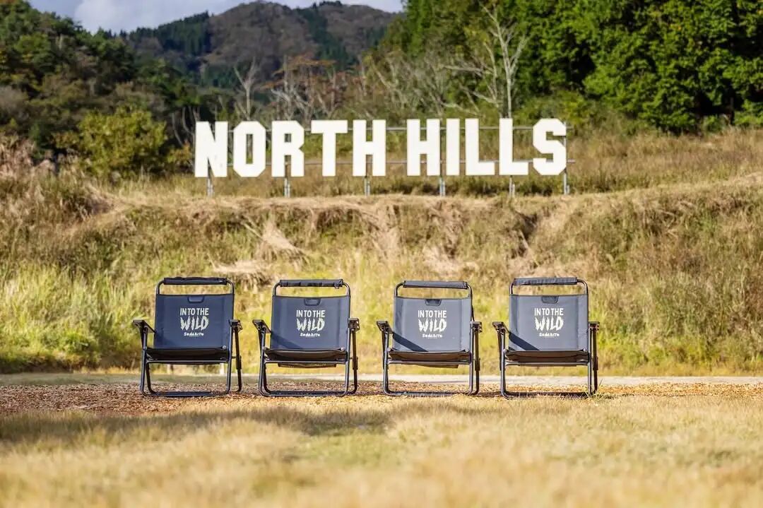 写有 NORTH HILLS 的草坡前摆放三把露营椅