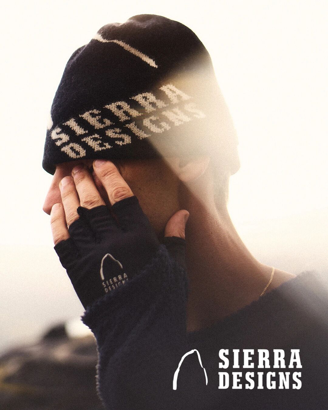 戴着 Sierra Designs 手套的人在户外抬手遮挡阳光