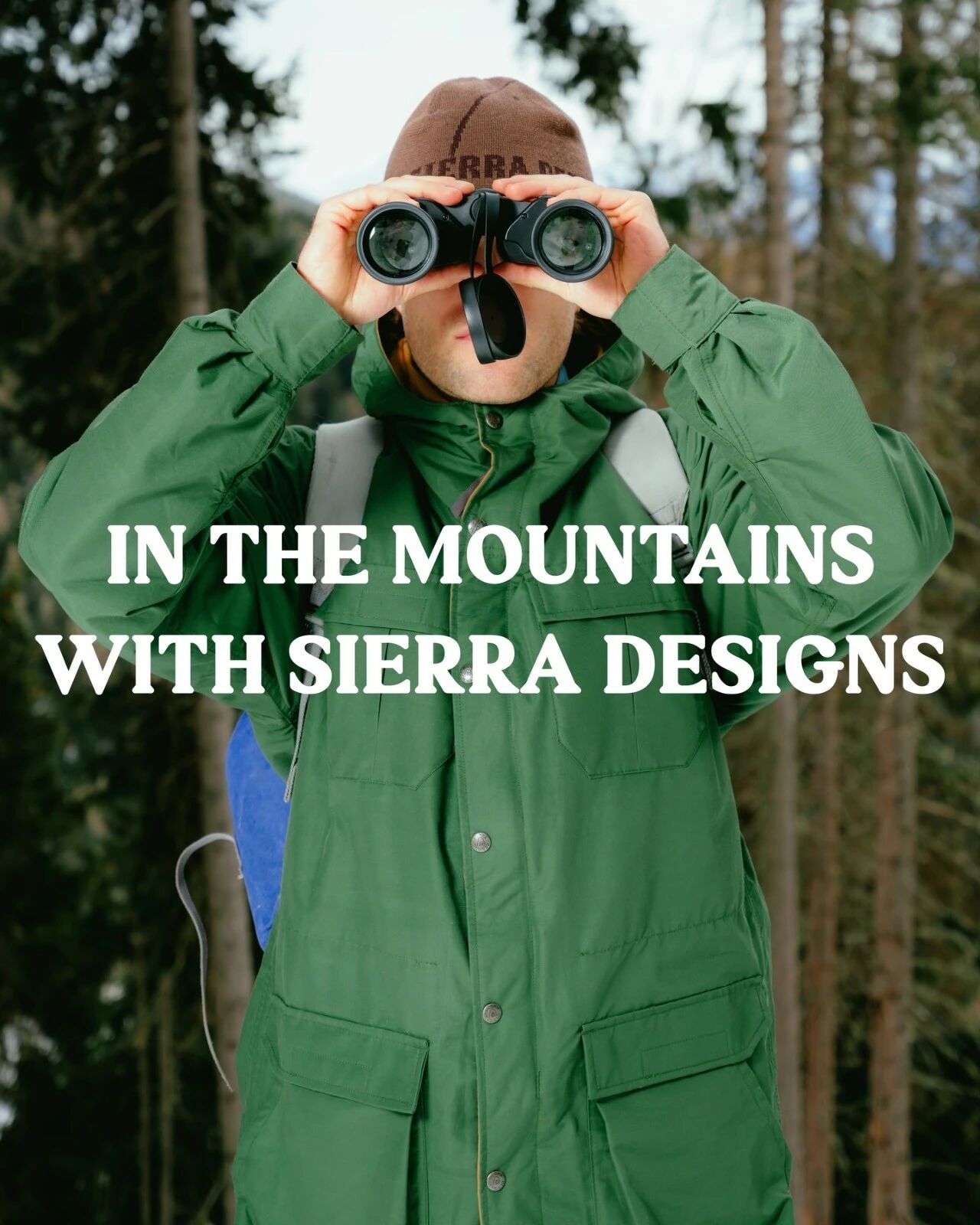 穿绿色 Sierra Designs 外套的人在山地环境举起相机